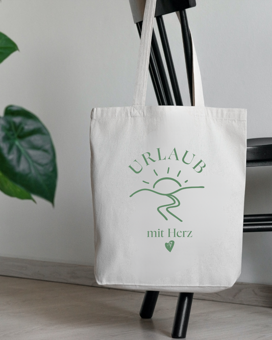 Baumwolltasche als Willkommensgeschenk für Gäste der Ferienwohnung, Aufdruck „Urlaub mit Herz" mit Sonnenmotiv.